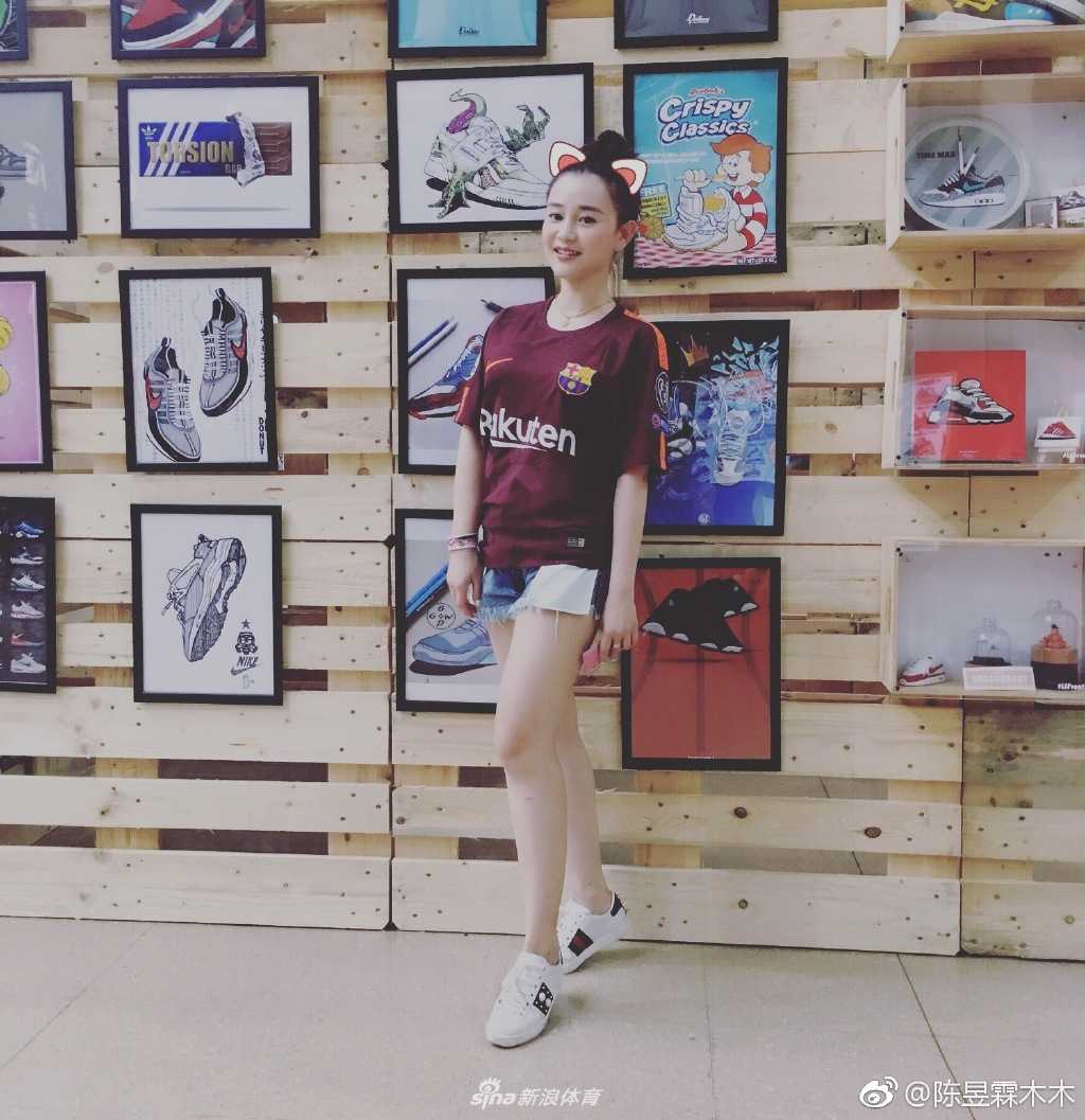 陈昱霖置身于一群朋友中间，大家共同围绕着一个巴萨队徽的蛋糕庆祝，她笑容满面，双手比出胜利手势，气氛热烈而欢快