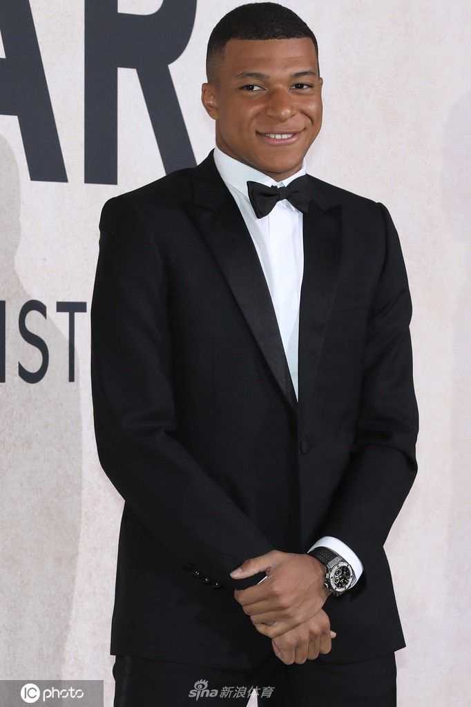 姆巴佩面对镜头展露标志性的阳光微笑，洁白的牙齿与深邃的眼神形成鲜明对比，传递出真诚与友善的信号。