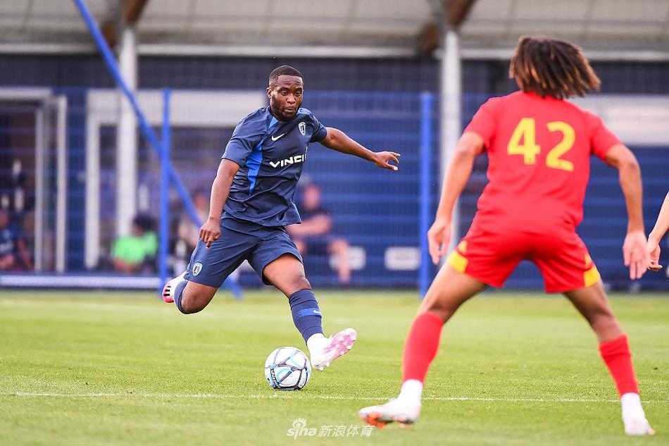 巴黎FC球员带球突破，勒芒防守球员紧身贴防，夏日夕阳下，两人肌肉线条紧绷，展现着足球对抗的力量与美感