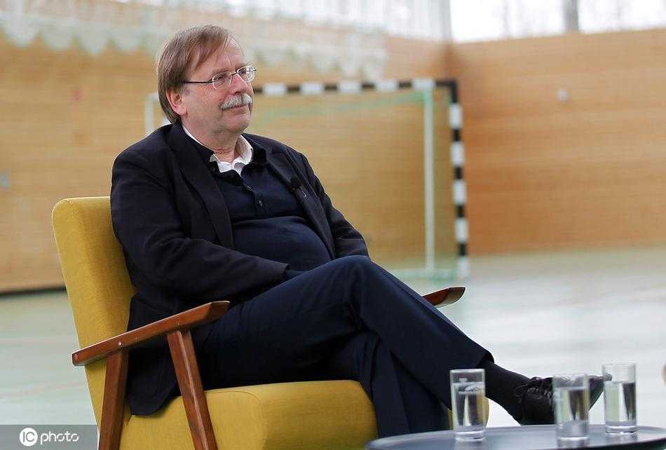 在室内的暖光下，拉姆单手轻触额头，举手投足间尽显优雅与睿智，仿佛在与记者分享一个关于足球与人生的深刻秘密。