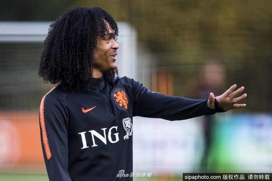 钟塔西身穿布鲁日训练服认真进行拉伸训练，身后的比利时清晨阳光洒在草皮上映照出他修长的身影