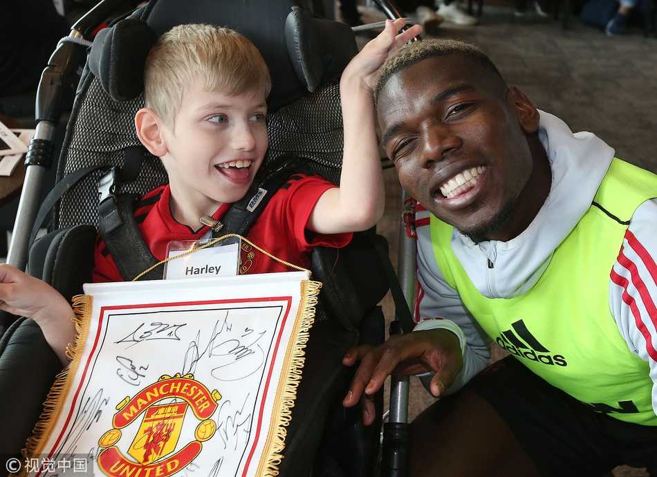曼联球星博格巴在梦想日活动中单膝跪地，平视着一位坐在轮椅上的小球迷，两人掌心相击，法国球星的眼神里满是鼓励与温柔，仿佛在说‘你也是我们的一员’。