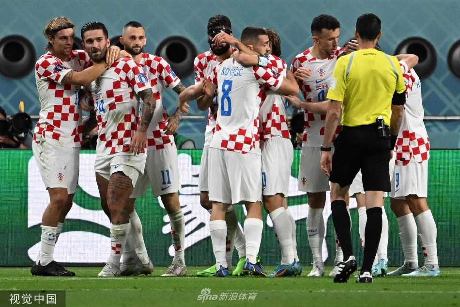加拿大球员阿方索·戴维斯虽打入历史性进球却难掩失利后的失落，他双手叉腰低头不语，与远处欢庆的克罗地亚队员形成鲜明对比。