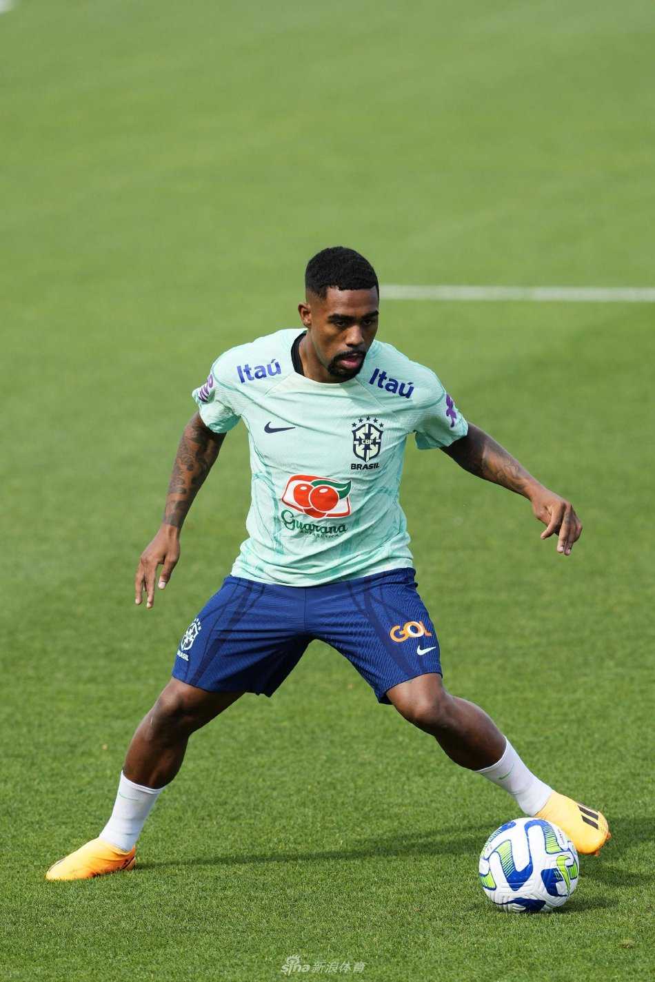 一位巴西球星在单独训练中展现卓越的脚下技术，他正专注地用脚背颠球，目光紧随跃动的皮球，背景是开阔的训练场和蔚蓝天空。