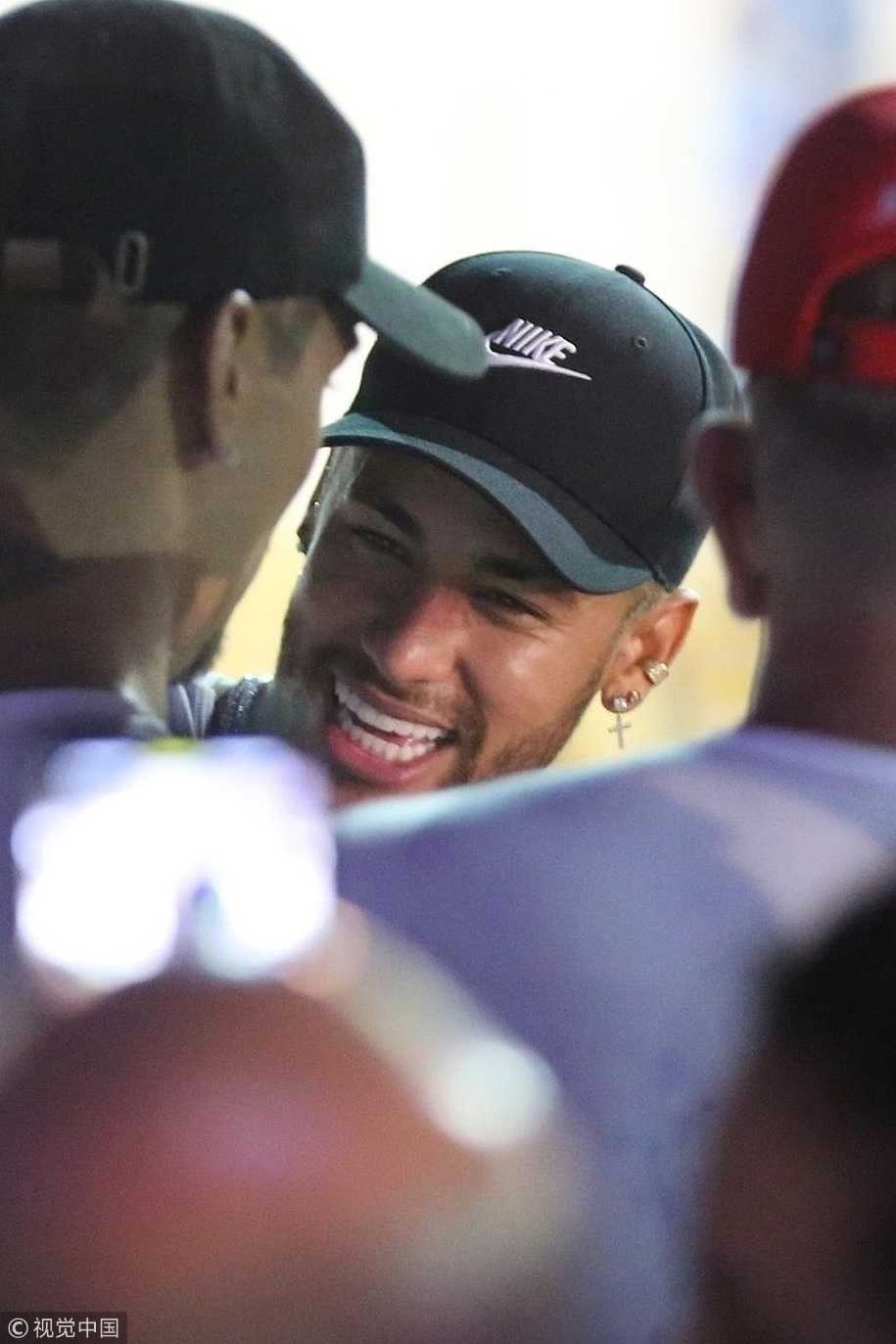 内马尔一手搂着一位金发美女，眼神中带着几分迷离与不羁，背景是里约华灯初上的夜景，仿佛整座城市的热情都被他点燃，化作了这璀璨灯火。