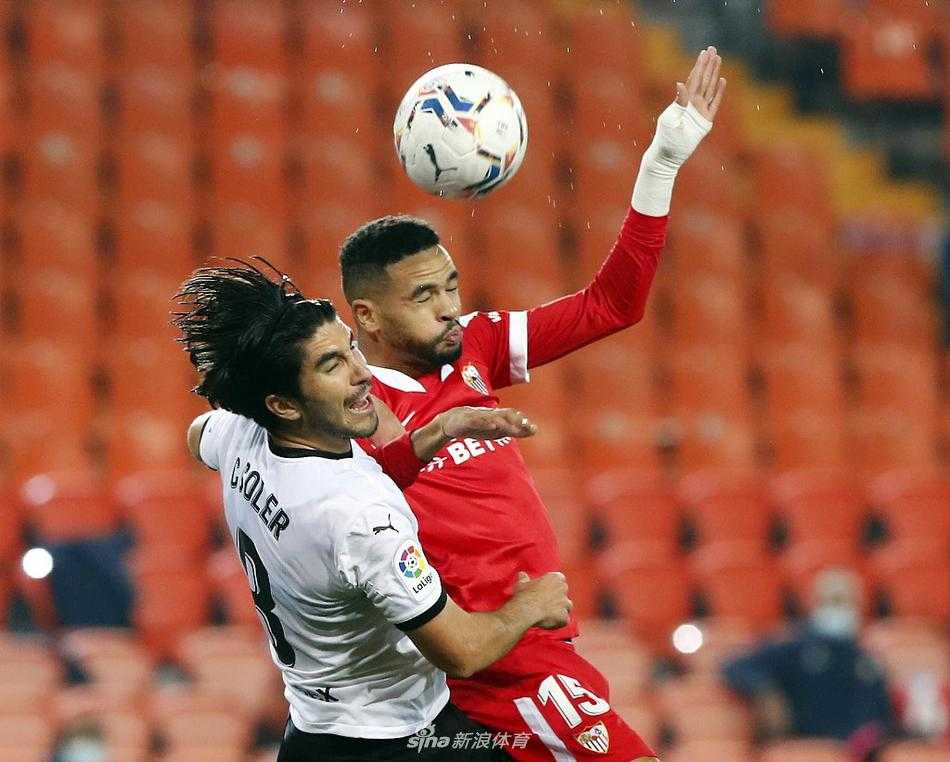 瓦伦西亚球员戈麦斯在争顶中奋力跃起，他的眼神中充满了对进球的渴望，但塞维利亚的防守球员如影随形，密集的人墙预示了蝙蝠军团全场进攻的艰难。