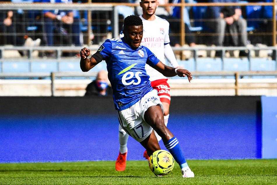 斯特拉斯堡前锋迪亚洛进球后激情滑跪，他身后的看台上是沸腾的球迷，双手紧握成拳，仿佛在向全队呐喊：比赛还远远没有结束，蓝白之心永不言弃！