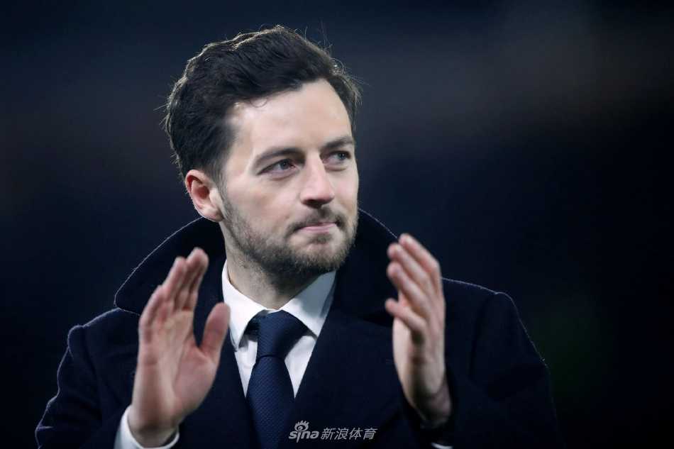 瑞安·梅森神情专注地站在场边，手持战术板，正在对热刺球员进行临场指导。