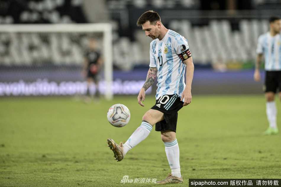 梅西双手指天，眼神中充满感激与坚定，身后的看台上是无数为他欢呼的阿根廷球迷，蓝白条纹在夜空中舞动