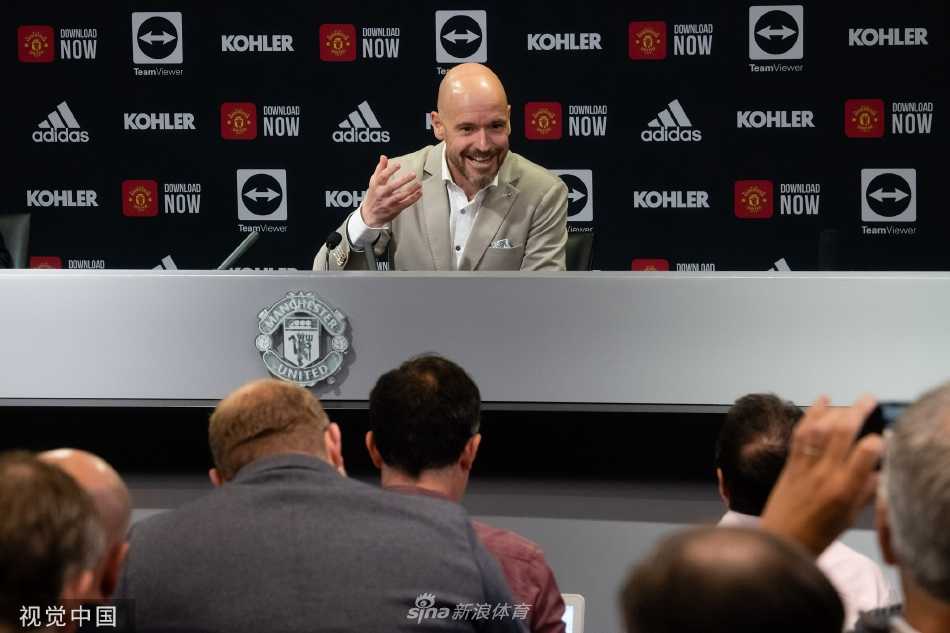 滕哈赫面带微笑，侧身站在老特拉福德球场的边线广告牌旁，目光望向远方，似乎正在憧憬着他即将在这片传奇草皮上指挥战斗的未来景象。