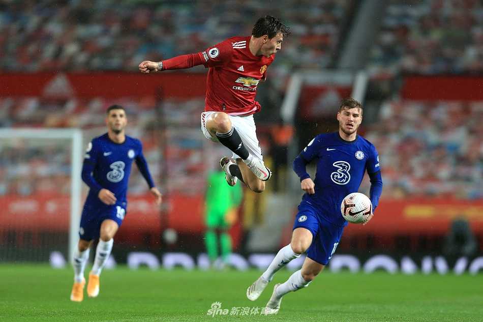 曼联与切尔西的球员们在老特拉福德的雨夜中激烈拼抢，脚下的草皮溅起阵阵水花，灯光下球迷看台上挥舞的围巾与雨滴交织成一幅湿漉漉的战场画卷。