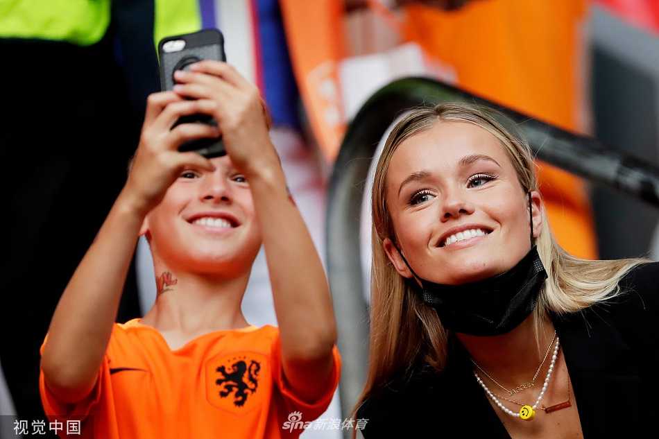 荷兰队球员的亲友团在看台上展示出一面巨大的荷兰国旗，她们的眼神中充满了对家人和祖国球队的支持。
