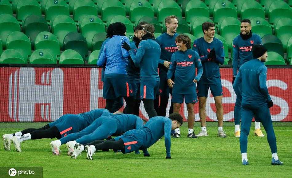 在克拉斯诺达尔的训练场上，一位塞维利亚球员正低头专注地调整着脚上的战靴，仿佛在与即将奔赴战场的“伙伴”进行最后的无声交流。