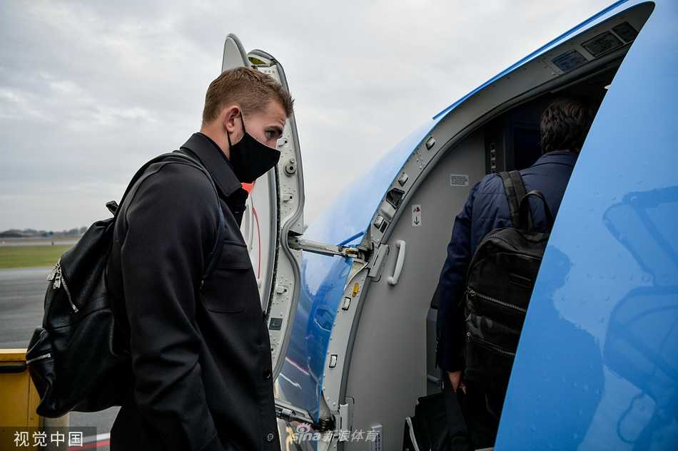 洛卡特利拖着行李箱独自前行，身后巨大的深色背景衬托出他坚定的侧脸，仿佛承载着球队中场重任。