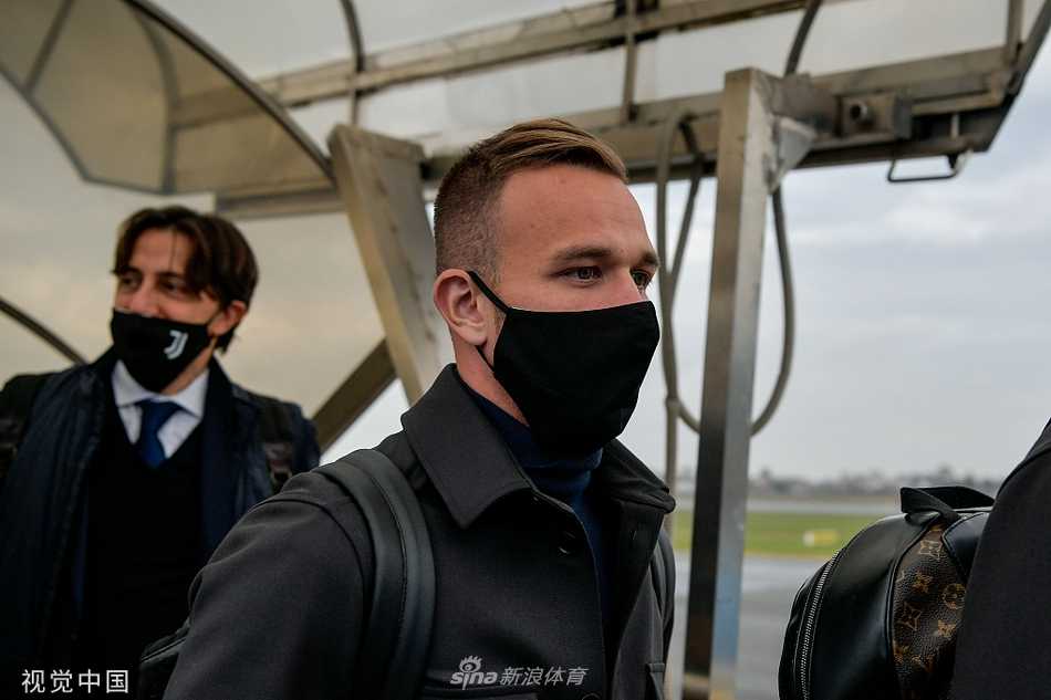 什琴斯尼戴着黑色墨镜，肩背巨大运动包，嘴角带着一丝若有若无的微笑，尽显门将的从容与冷静。