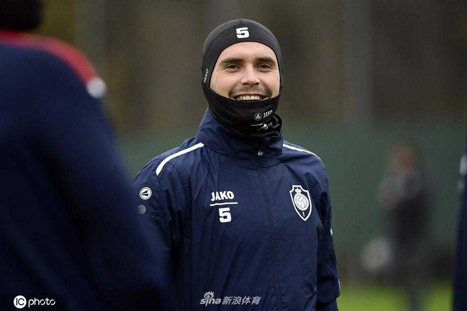 球员进行拉伸，身体线条紧绷，面部表情专注，背后的训练器材静默排列