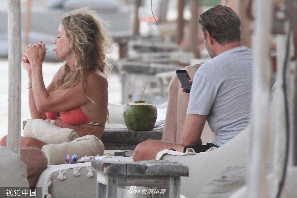 克洛普和妻子乌拉在海浪边赤脚行走，留下欢乐的脚印，他一手提着鞋，一手牵着爱人，仿佛忘记了所有赛场上的压力，完全沉浸在度假的欢愉中。