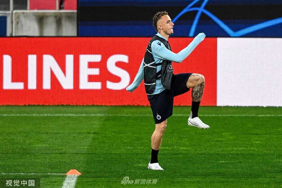 守门员飞身侧扑，指尖奋力触及皮球，门将训练区水花与草屑齐飞