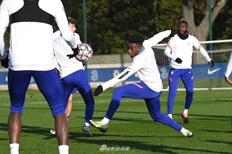 主帅兰帕德双手叉腰，神情严峻地站在场边督战。他的目光穿透镜头，仿佛正透过训练的表象，审视着每一个战术细节。头顶的灯光为他勾勒出一道剪影，那是背负着豪门复兴重任的坚定轮廓。