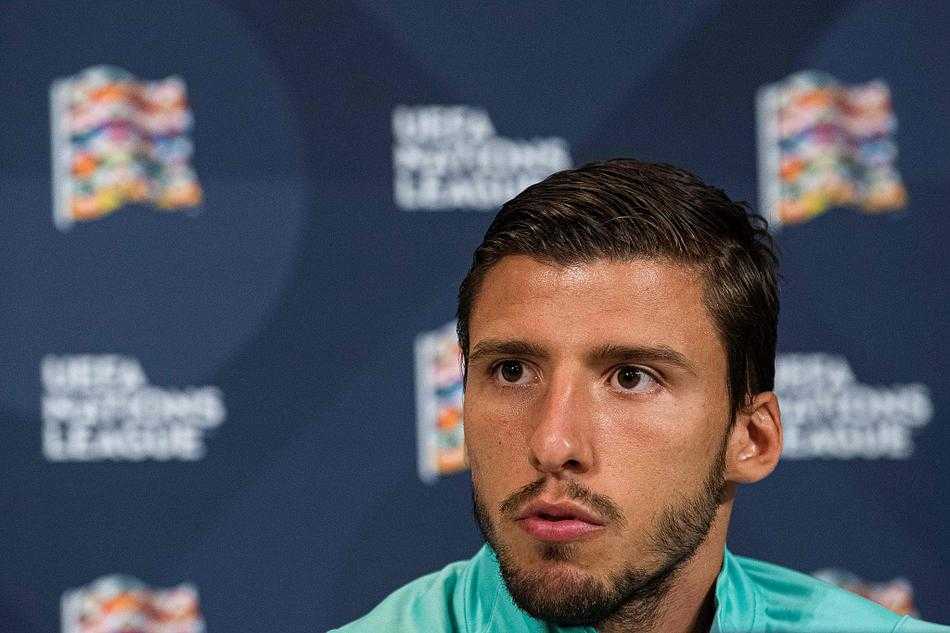 鲁本·迪亚斯端坐在发布会桌前，年轻的面庞上写满了与年龄不符的沉稳，他身後的葡萄牙队徽在灯光下熠熠生辉，预示著後防新核即将扛起球队的钢铁防线。