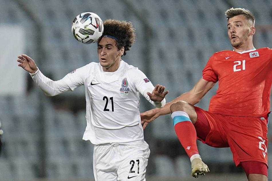 卢森堡与阿塞拜疆球员在寒夜中激烈争顶，球衣紧贴身躯，眼神专注，仿佛连呼吸都凝固在这一刻的争抢中。