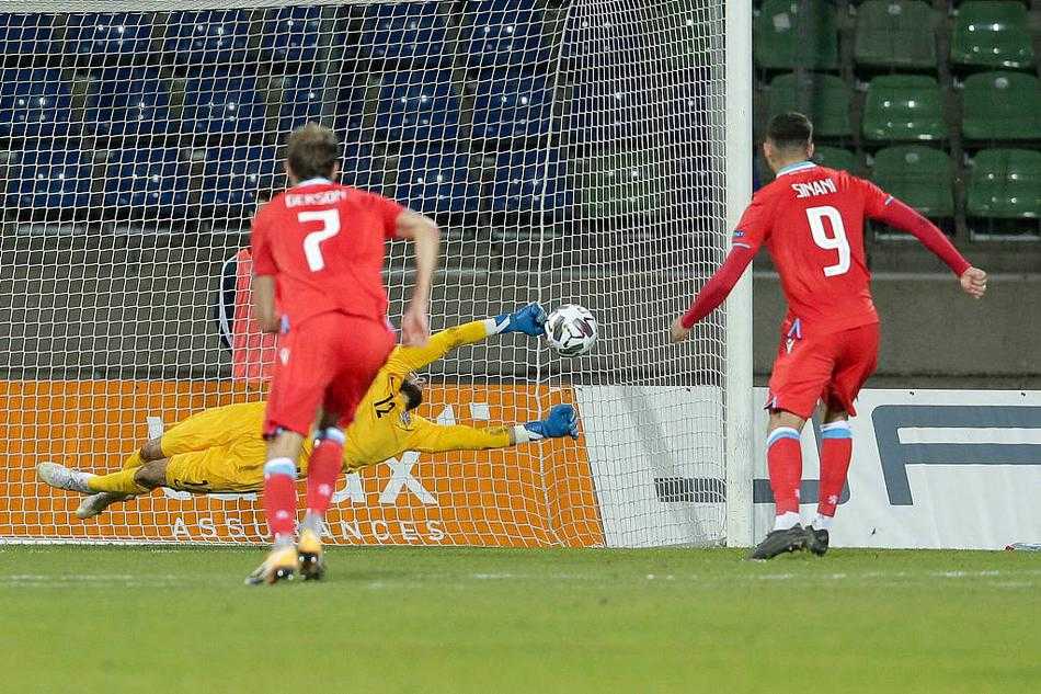 卢森堡队长洛朗·扬斯在拼抢中倒地，身边的草皮因激烈的对抗而翻起，他依然昂首指挥队友，眼神中透露出对胜利的渴望。