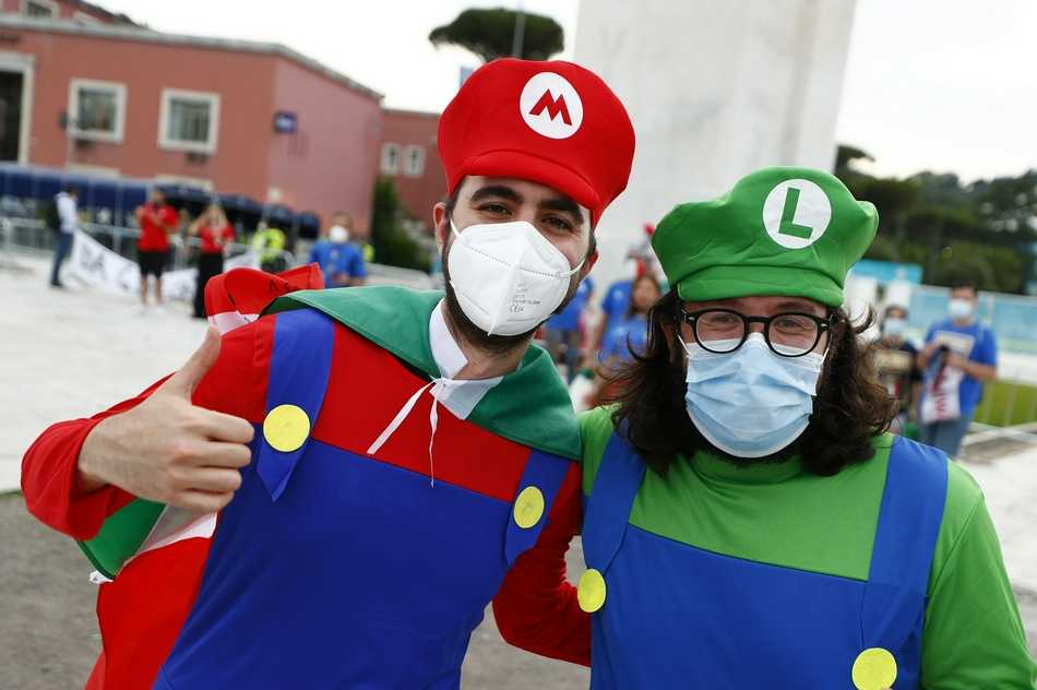 在人声鼎沸的球场看台上，两名身着不同球队球衣的球迷紧紧相拥，他们的表情既紧张又充满关切，目光没有看向赛场内的角逐，而是共同注视着场边发生的意外，这一刻 rivalry 已不再重要