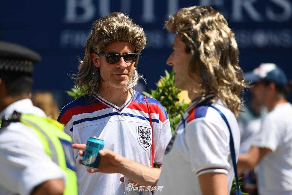 标准的金发碧眼美女造型，精致的妆容配上一字肩连衣裙，然而那宽阔的肩膀和粗壮的手臂却暴露了其男性的身份，他正和同伴们一起为球队的精彩表现振臂高呼。