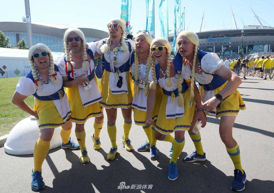 这位老兄选择了邻家少女风格的碎花吊带裙，配上可爱的丸子头假发，正全神贯注地盯着赛场，这身装扮让他成功吸引了转播镜头的注意，成为场外的绝对焦点。