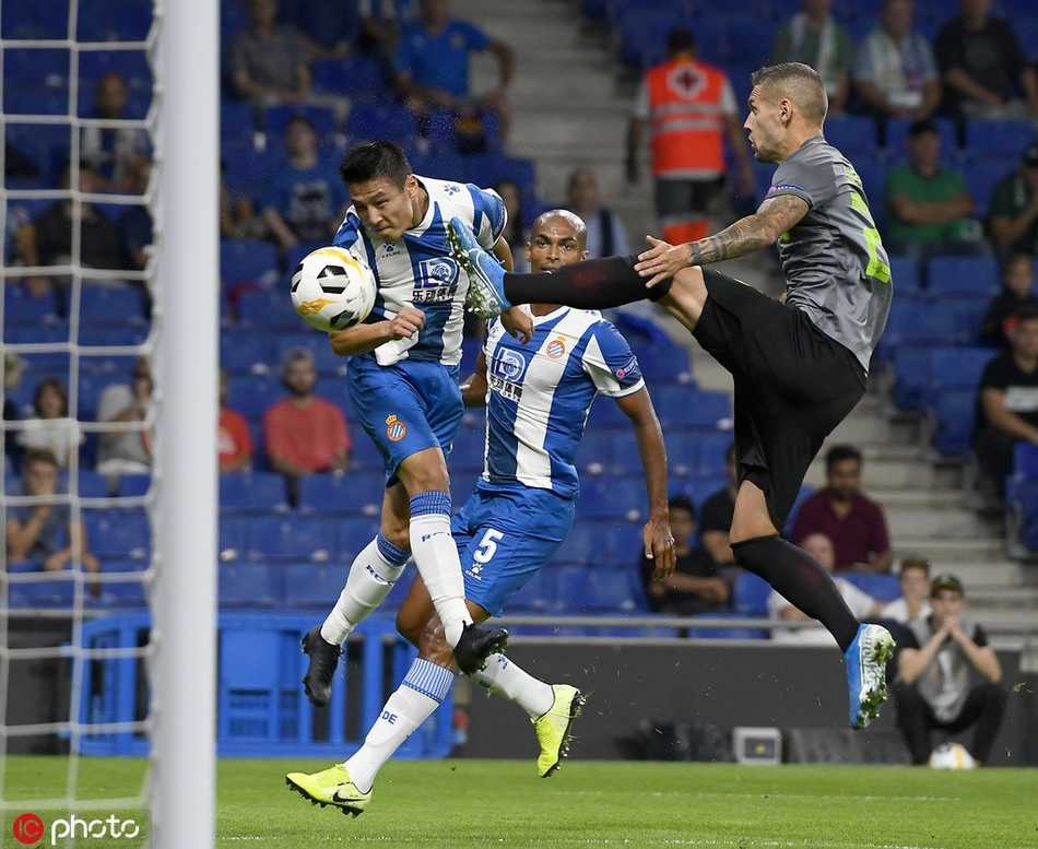 武磊在对方严密防守下带球突破，他压低重心，眼神坚毅，试图撕开对手的防线