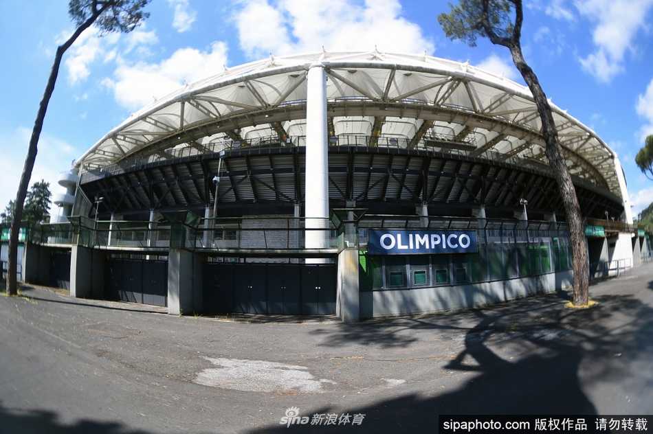 从球场内部看台视角望去，阳光透过顶篷洒在绿茵场上，一排排空无一人的红蓝座椅静静等待，仿佛能听到下一次球迷涌入时那山呼海啸般的欢呼与歌声。