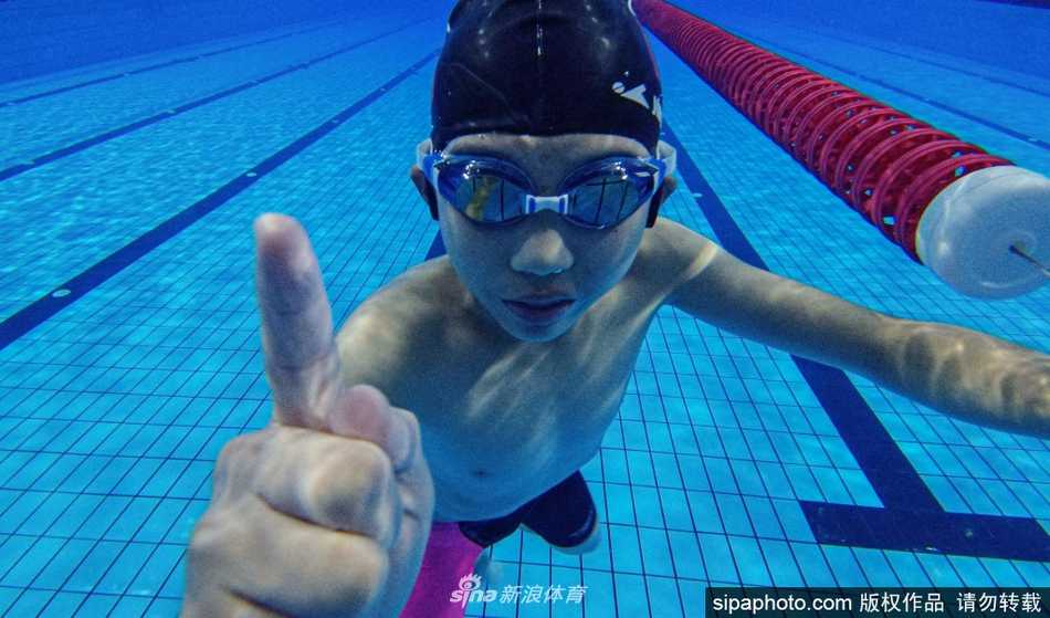 在沈阳体校的游泳馆内，清澈的泳池中水花四溅，几名佩戴泳帽和泳镜的少年奋力向前游进，他们身后的水痕仿佛是梦想划过的轨迹。