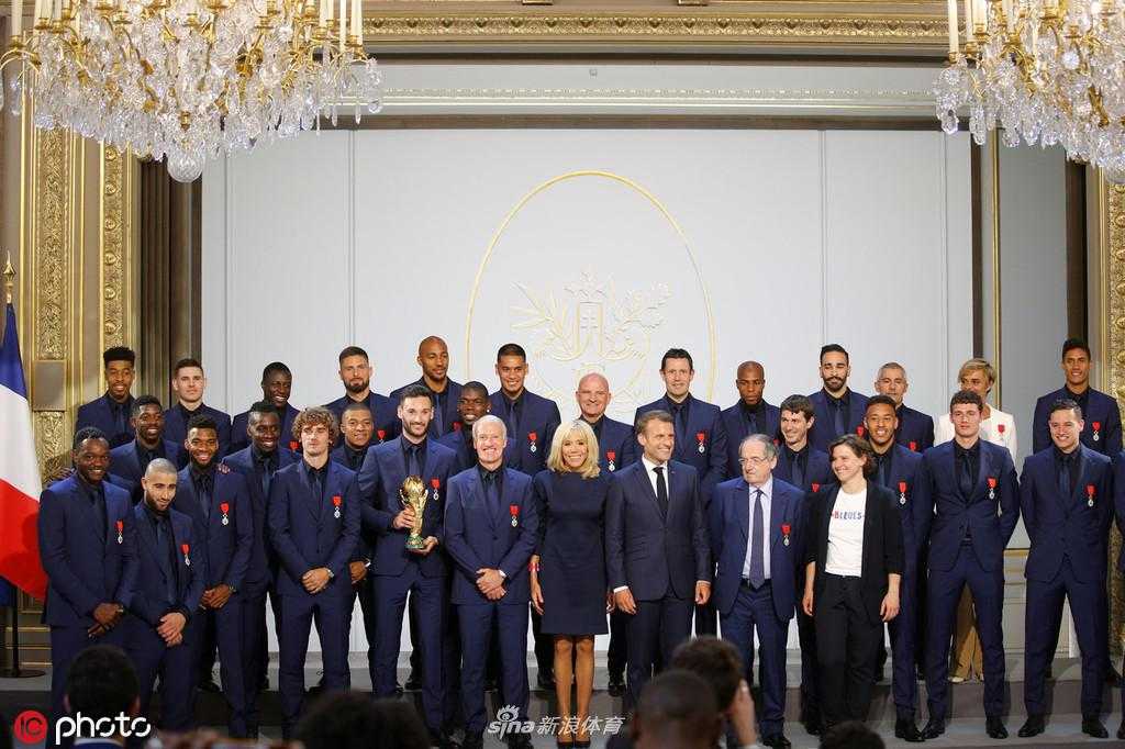 基利安·姆巴佩身着剪裁得体的深蓝色西装，胸前的荣誉军团勋章格外显眼，他面带标志性的微笑，眼神中既有年轻人的朝气，又有世界冠军的沉稳。