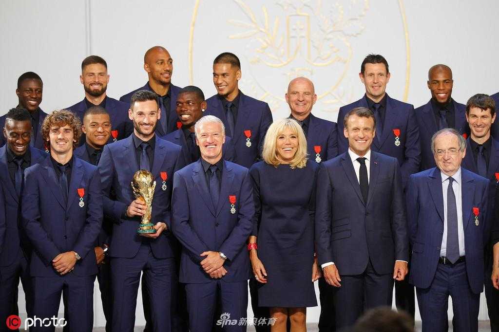 德尚教练与球员们围成一圈，共同展示刚刚获得的荣誉军团勋章，金色的勋章在红色绶带衬托下格外庄重，团队的凝聚力和自豪感在空气中弥漫。