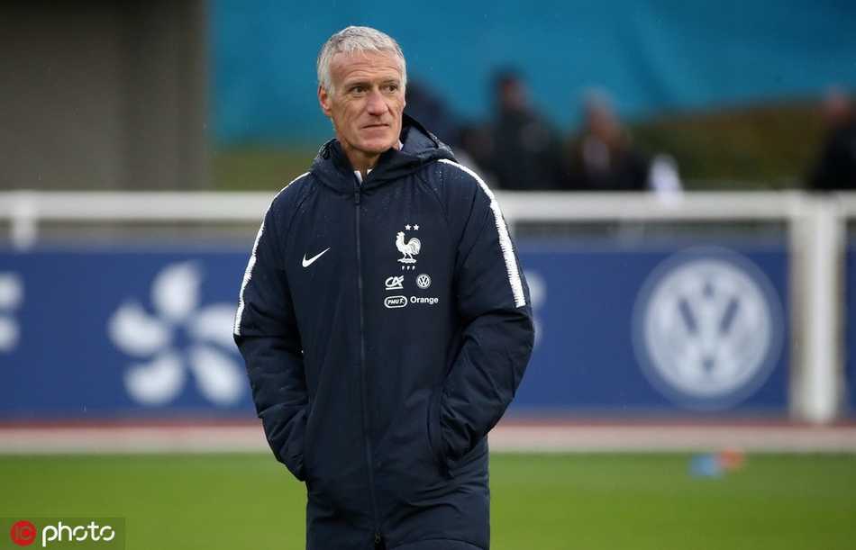 法国队球星格列兹曼面带微笑在训练中控球，场边围满了高举手机和围巾的球迷