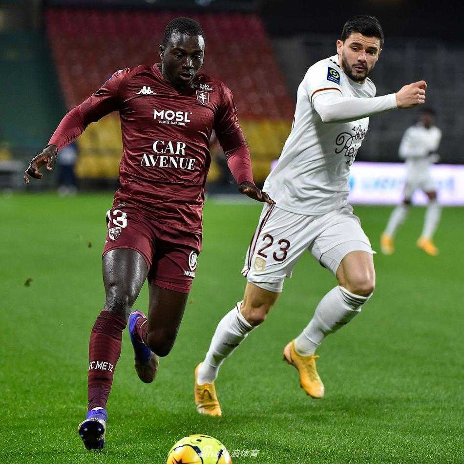 圣塞弗伦球场的雨夜，灯光下的草皮泛着水光，主队梅斯的球员们正围成一圈，神情专注地聆听队友的赛前动员，空气中弥漫着大战前的紧张与肃穆。