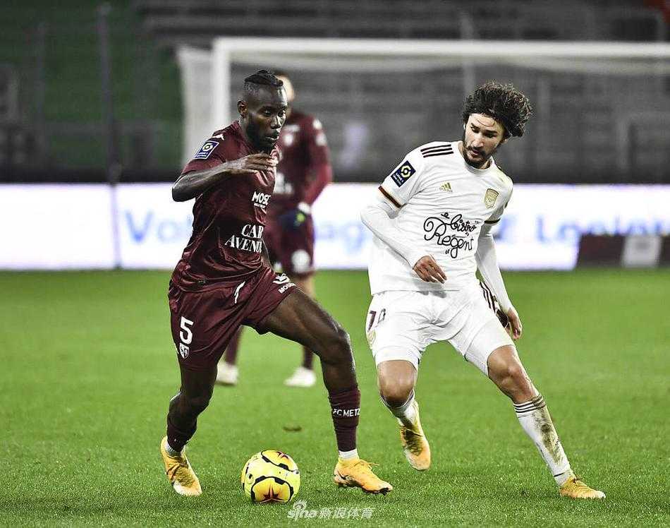 比赛结束，客队波尔多的球员们低着头，难掩失望之情，他们身后是梅斯队的工作人员正在为场地浇水维护，背景中的巨大广告牌在夜色中格外显眼。