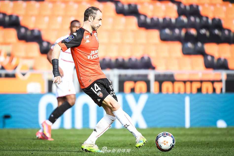 镜头聚焦于赛场上的拼抢瞬间，一名球员在高速带球中遭到对手的侧后方铲抢，皮球被破坏出边线，带球球员失去平衡的瞬间，场边的广告牌清晰可见。