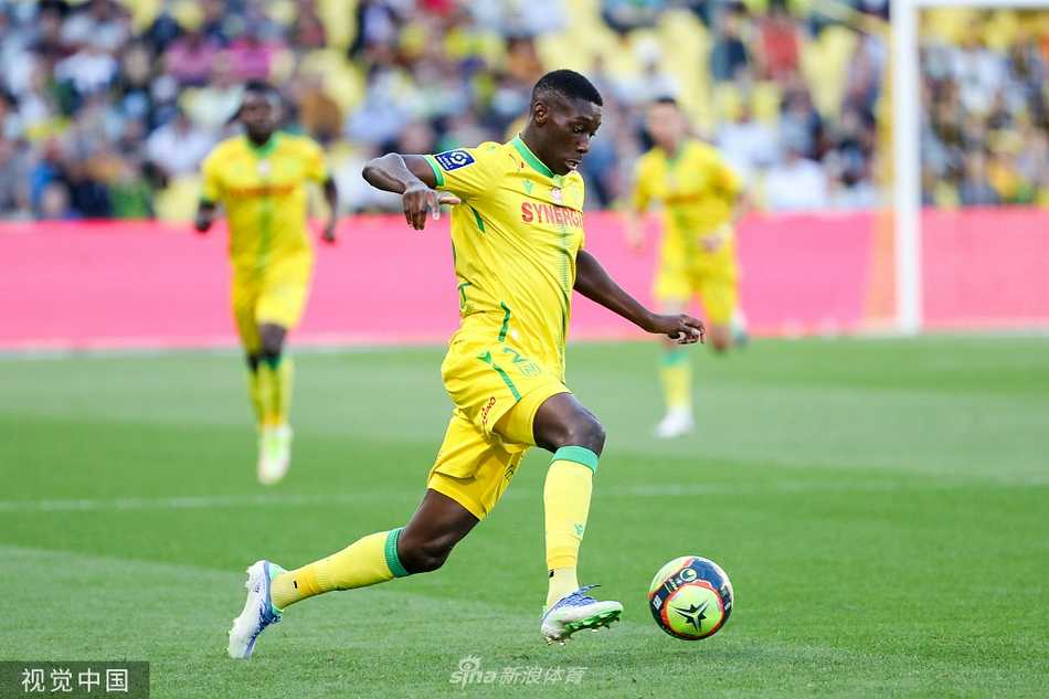 路易斯·冯特奴球场在夜色中灯火通明，南特队主场迎战布雷斯特，看台上绿色的座椅与球迷挥舞的旗帜构成一幅充满活力的画面。