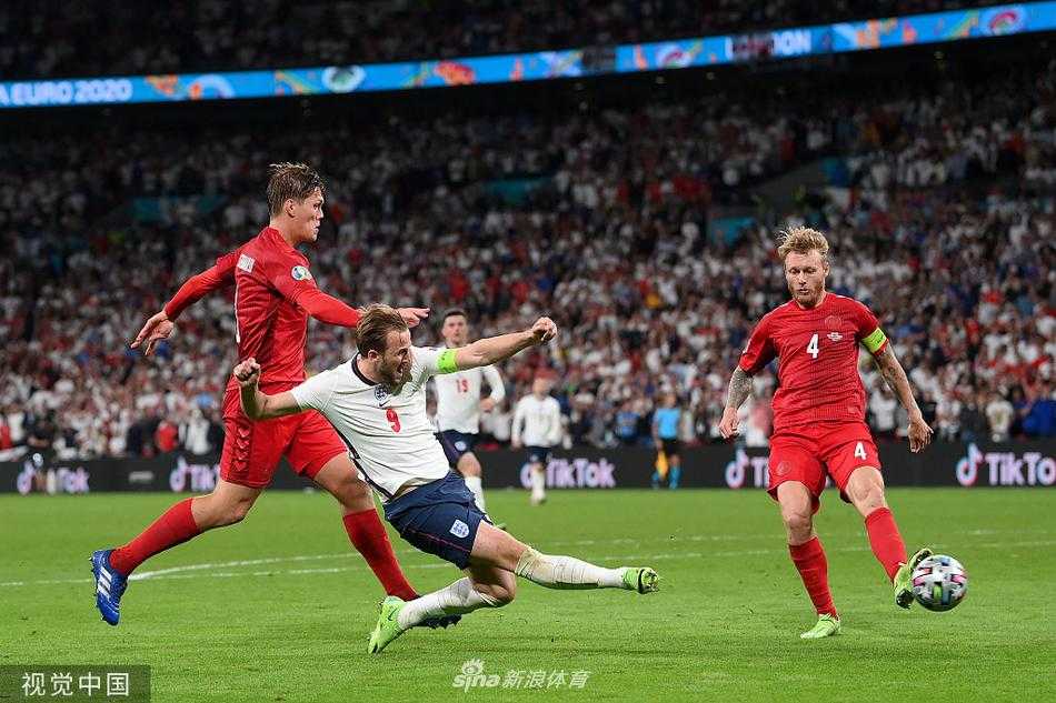 英格兰队长凯恩主罚点球，他眼神坚定，助跑后起脚射门，丹麦门将舒梅切尔虽然扑出了皮球，但凯恩迅速跟进准备补射，门前一片混乱。