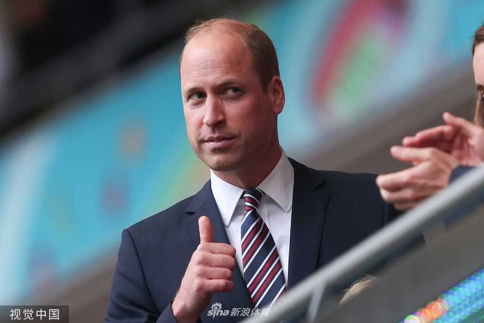 比赛尚未开始，威廉王子与凯特王妃的脸上写满了专注与期待。威廉王子眼神深邃，似乎预感到这场比赛的艰难；而凯特王妃则报以标志性的优雅微笑，但微微握紧的双手还是暴露了她内心的紧张。身旁的乔治小王子正襟危坐，如同一个缩小版的绅士，好奇地打量着这个即将被足球热情点燃的夜晚。