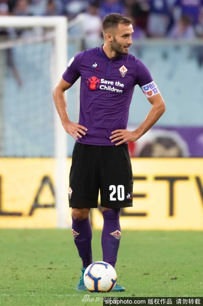 在室内训练馆中，佩泽拉手握贝蒂斯训练服看向镜头，嘴角带着微笑，胸前的队徽在灯光下格外醒目