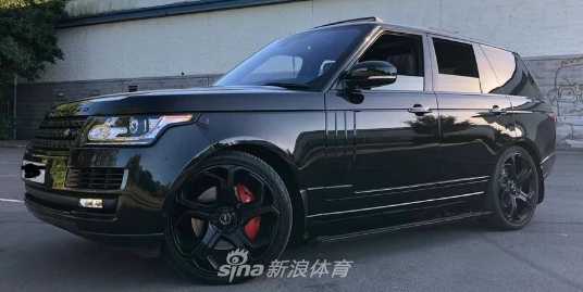 一辆豪华品牌的中大型SUV停在户外，车身宽大沉稳，深色的车漆反射着周围的景色，透露出一种低调而内敛的强大气场。