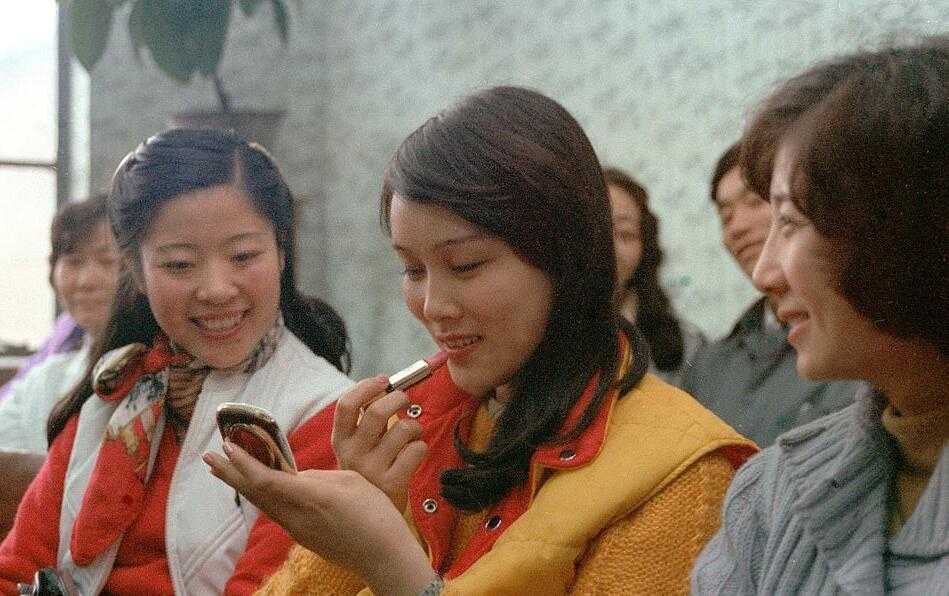 露美美容厅内，几位年轻的女青年正在对着镜子专心致志地练习涂口红，桌上摆满了那个年代刚刚出现的国产化妆品，脸上写满对新生活的憧憬。