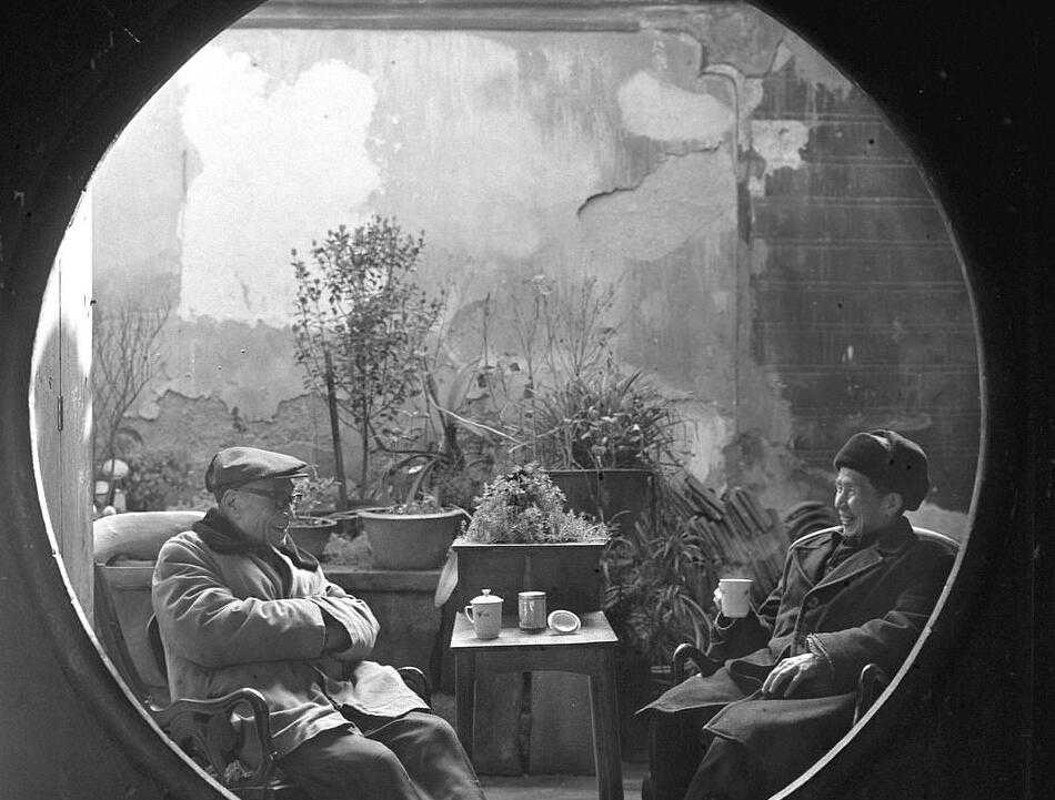 一位身着笔挺西装的男士，神情自信地手持一部“大哥大”在通话，这部砖头般厚重的移动电话在当时是身份与财富的绝对象征。