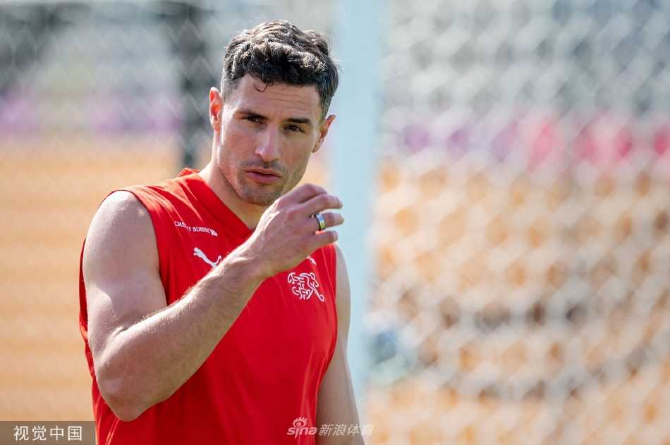 训练间隙球员们进行拉伸放松，背景是卡塔尔现代化的训练基地，氛围严肃而专业