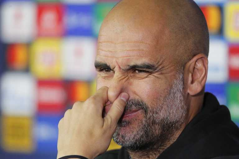 瓜迪奥拉侧身对着镜头，眉头微挑，嘴角扬起一个标志性的神秘微笑