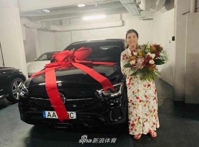 幸福满溢，C罗母亲多洛雷斯怀抱美丽鲜花，身旁是一辆系着巨大红色蝴蝶结的崭新黑色奔驰，她笑容灿烂，享受着孩子们为她精心准备的母亲节惊喜。
