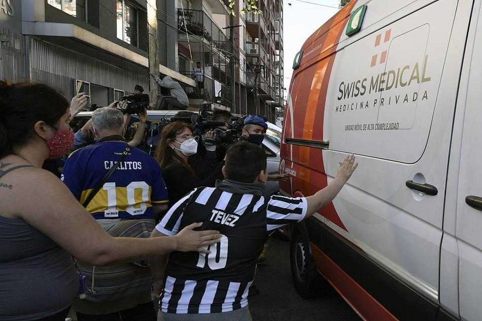 救护车在狭窄的街道上寸步难行，两侧是几乎要贴到车身上的狂热人群。有人甚至试图伸出手，去触摸那冰冷的车身，仿佛这样就能把力量传递给心中的英雄。蓝色的警灯和黄色的救护车灯在人群中交替闪烁，映照出一张张既兴奋又担忧的脸。