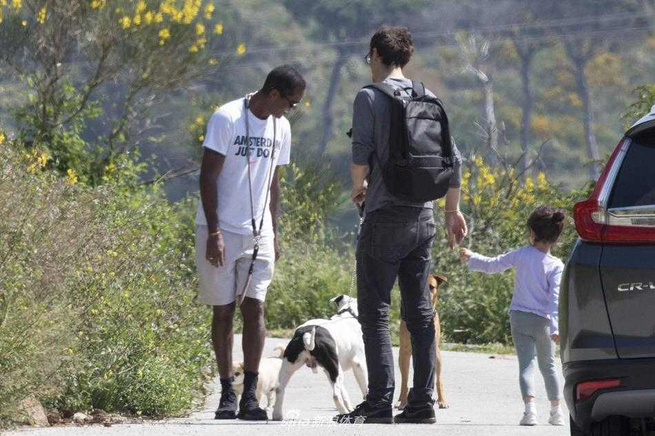 克鲁伊维特低头温柔地看着自己的宠物狗，狗狗欢快地向前跑动，牵引绳在阳光下被拉直，画面充满了生活气息